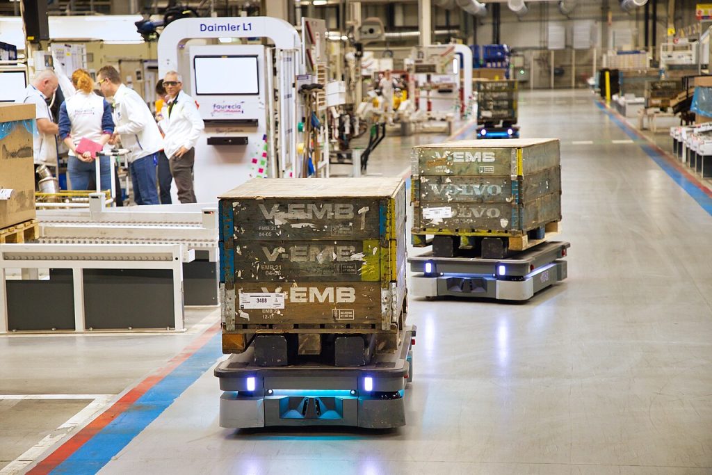 MiR250 autonomous mobile robots transport loaded pallets through a Forvia factory. / Autonomni mobilni roboti MiR250 prevoze pune palete kroz fabriku kompanije Forvia.
